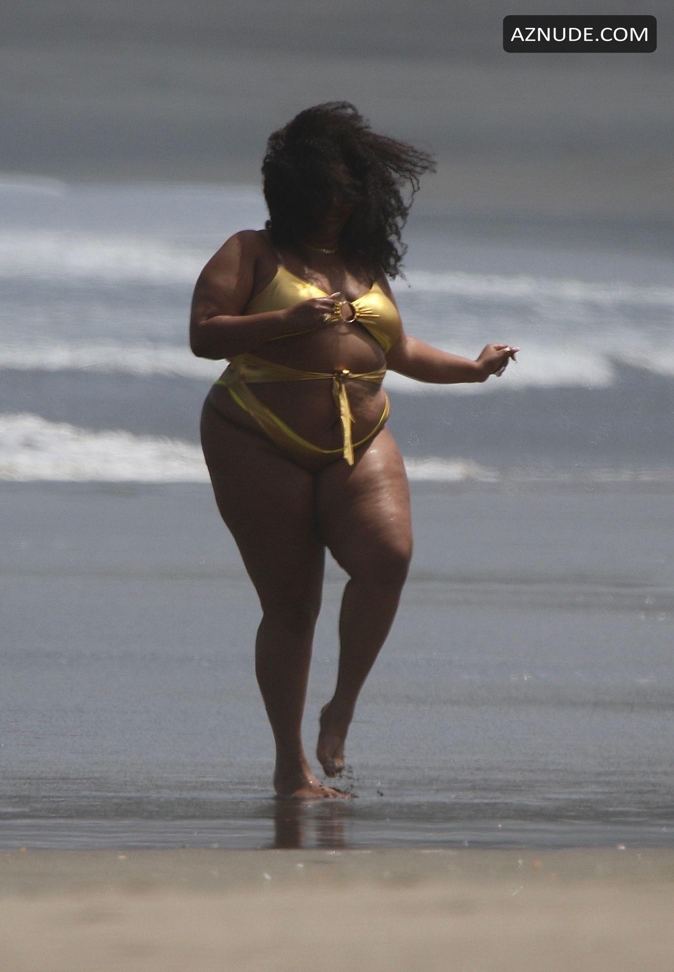 Lizzo Stands In A Tiny Metallic Gold One Piece Whilst With Her Entourage At Piha A Famous Surf